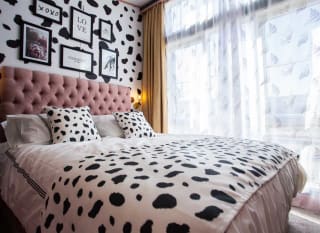 A double bedroom with cow spot print feature wall and continued on the bedding with light pink duvet covers. image