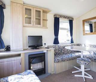 The dining and living area of one of our budget-friendly value static caravans. The perfect way to stay.