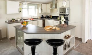 The interior of one of our Luxury holiday lodges. There's a kitchen area with many appliances, and an island in the centre. image