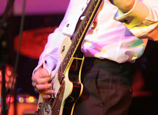 A close up image of a man playing a guitar. image