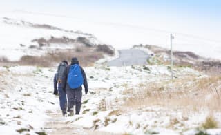 Two people taking a snowy winter walk at our Isle of Wight park, The Bay Colwell. image