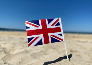 A union jack flag in the sand on a sunny day.