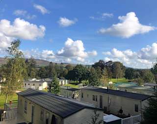 An aerial view above the roofs of holiday caravans in Moffat Manor, with hills in the distance. image