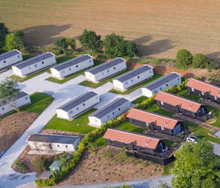 An aerial view of a lake with holiday homes surrounding the lake, with caravans in the distance.