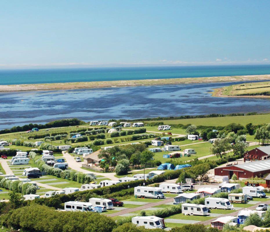 A bright sunny day overlooking our East Fleet Farm holiday park in Dorset. There are vast areas of countryside and a river to the horizon.