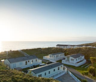 Two rows of caravans with views of the sea and the sun setting at our holiday park in North Wales, Barmouth Bay.