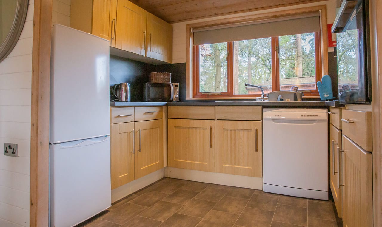 The interior of one of our Luxury holiday lodges. There's a kitchen area with many appliances, and an island in the centre. image