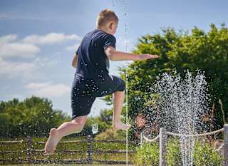 Child jumping into splash pad at Appletree Holiday Park. image
