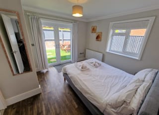 A double bedroom in one of the rooms within our cottages. opposite the double bed are french doors that lead to a garden area. To the right of the bed is a window, also looking out to the garden area. image