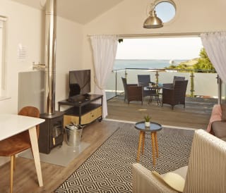 The living area of one of our spacious Beach Lodges, with stunning views of the sea from the balcony. Book your holiday now!