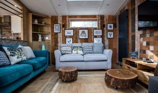 An image of the interior of one of our luxury holiday lodges as part of the May Bank holiday offer. The walls have wood panneling and there's pair of blue and grey two seater sofas. image