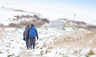 Two people taking a snowy winter walk at our Isle of Wight park, The Bay Colwell.