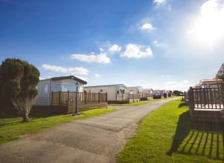 A wide pathway with holiday caravans on either side. Blue skies above. image