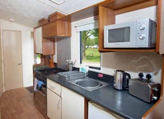 The kitchen area of our budget-friendly value static caravan. The perfect way to stay. image