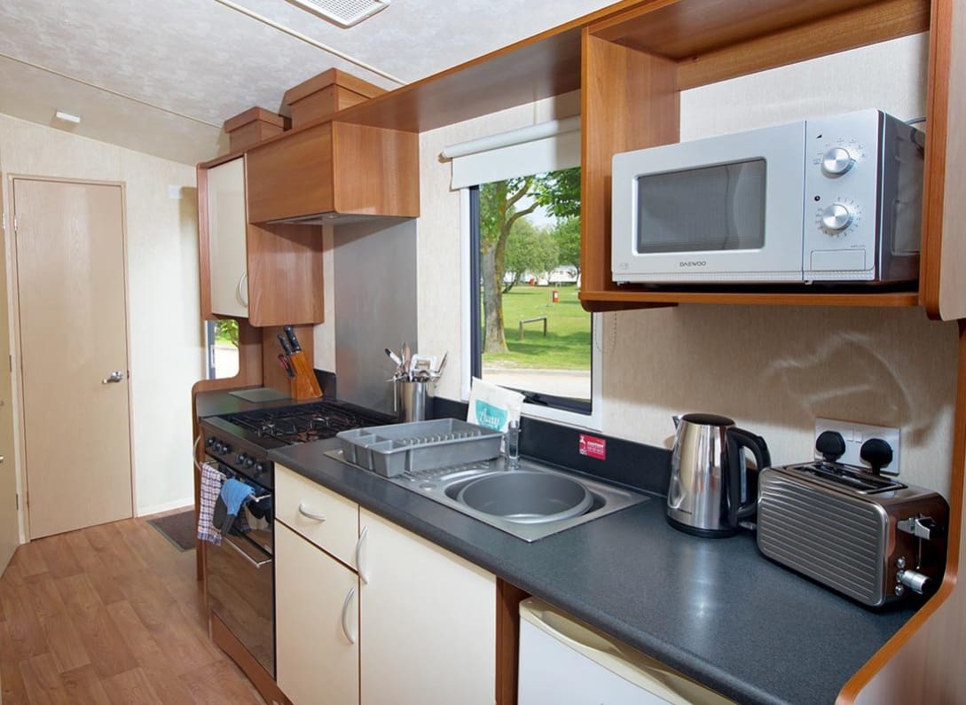 The kitchen area of our budget-friendly value static caravan. The perfect way to stay. image
