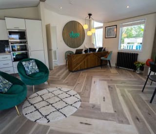 An interior view of inside the Away Resorts Holiday Homes sales office. There is a wooden reception desk, teal blue seats and a wooden sign above the desk saying, 