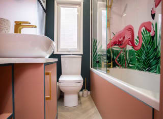 A clean and white bathroom with pink wooden accents on the washbasin and bathtub. The white shower curtain has a pink flamingo on it. image