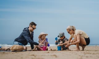 A family enjoying a summers day on the beach. There is a mother and father and two young children. image