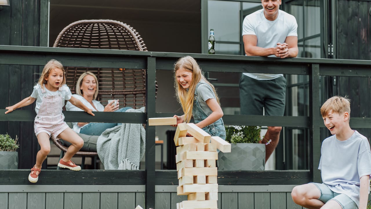 A family of five playing a game of jenga outside their accommodation.