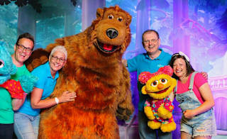 A group of people posing for a photo with the Away Resorts characters, Bear, Scratch and Lucy. image