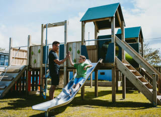 A father and son playing in the outdoor playground at our Bude Holiday Resort, Cornwall. image