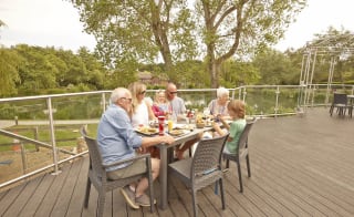 A family sat in the outdoor seating area at The Lakeside Bar & Eatery on a summers day at our park in the Isle of Wight, The Lakes Rookley. image