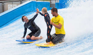 A family enjoying a surf on the Flowrider at our Cornish Resort, Retallack Resort & Spa.