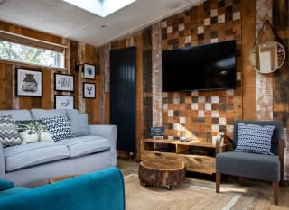 The lounge area in The Knightwood holiday lodge. This lodge has large sofas, a flatscreen TV, and plenty of rustic, woodland décor to enjoy. image