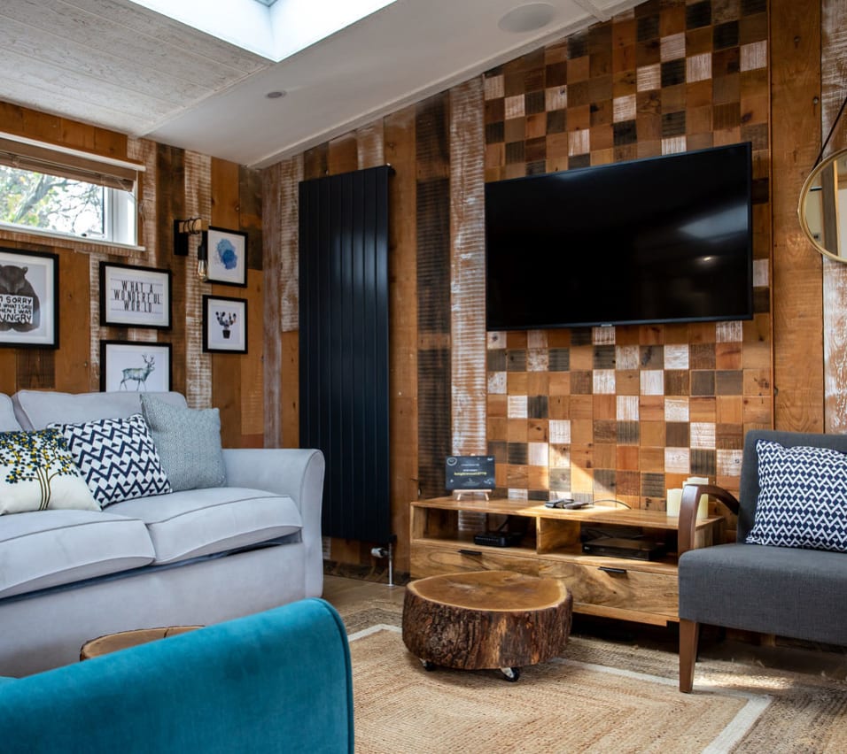 The lounge area in The Knightwood holiday lodge. This lodge has large sofas, a flatscreen TV, and plenty of rustic, woodland décor to enjoy. image