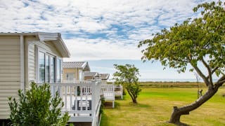 A row of caravans at our park in Essex, Mersea Island, with views of the sea in the background. image
