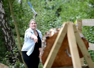 A lady taking part in the target axe throwing activity. image