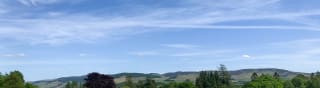 Our Moffat Manor holiday park. There are several luxurious holiday homes onsite, with tall trees and hills in the background. image