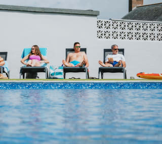 A family enjoying a sunny day at the outdoor heated pool at Bude Holiday Resort. image