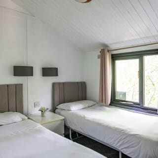 The interior of one of our Comfort holiday lodges. There's a twin bedroom with a side table and large window.