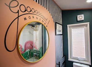 A round wall mounted mirror with the words,'' Good Morning'' painted on. image
