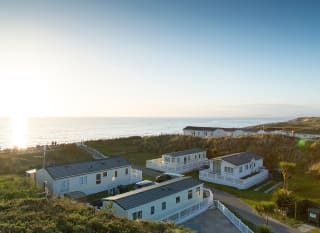 Two rows of caravans with views of the sea and the sun setting at our holiday park in North Wales, Barmouth Bay. image