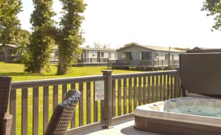 The decking with a hot tub of one of our stunning accommodations at St Helens Coastal Resort. image