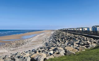 Our Golden Sands holiday park. The long beach stretches far into the distance, with rocks running along one side, and the sea on the other. image