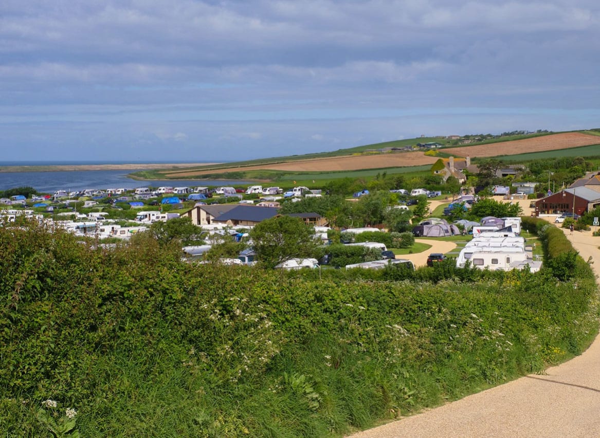Mobile caravans parked with a wide angle view of the vast countryside and the lagoon located at our East Fleet Farm holiday park in Dorset. image