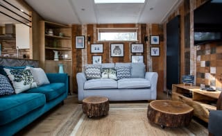 An image of the interior of one of our luxury holiday lodges as part of the May Bank holiday offer. The walls have wood panneling and there's pair of blue and grey two seater sofas. image