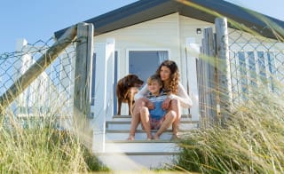 A mother, son and their chocolate lab dog sitting on the steps of one of our static caravans. image