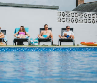 A family enjoying a sunny day at the outdoor heated pool at Bude Holiday Resort.