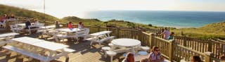 The outdoor eating area of our restaurant at St Ives Bay Holiday Park, with views of the sea. image