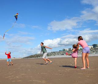 A family of four playing on the beach at our North Wales holiday park, Golden Sands.
