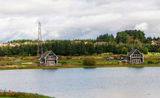 A view of the golf course at our stunning Scottish resort, Piperdam, on a cloudy but sunny day. There are views of lodges in the distance overlooking the lake and golf course. image