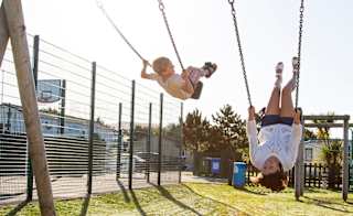 A mother and son on the swings at one of our holiday parks. image