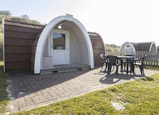 Exterior of our camping pod at St Ives Bay, Cornwall. A table and chair is located on the right, the perfect spot for brunch in the sunshine. image