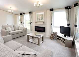 The interior of one of our Luxury holiday lodges. There are two large sofas, a TV, and plenty of space around a coffee table. image