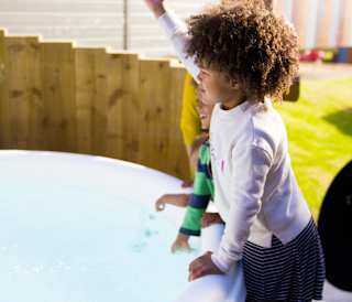 Three young children playing outside one of the hot tubs at our Whitecliff Bay holiday park.