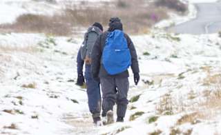 Two people taking a snowy winter walk at our Isle of Wight park, The Bay Colwell. image